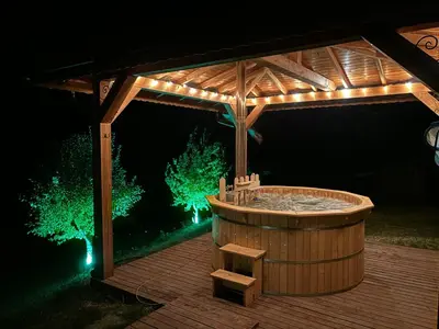 a hot tub under a wooden pergola at night at Вила Белият камък - Златоград in Zlatograd