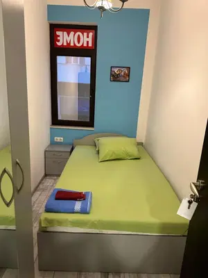 a small bedroom with a green bed with a window at Comfort Guest Rooms in Plovdiv