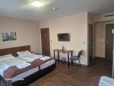 a bedroom with two beds and a desk and a television at Хостел Стадиона in Pazardzhik