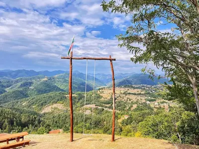 a swing on a hill with a bench and mountains at ВИЛА ЯНА Villa Yana in Presoka