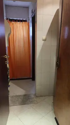 a bathroom with an orange shower curtain and a door at Apartments in Ramada 2 Complex in Bansko