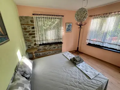 a bedroom with a bed and two windows at Вила Динати in Perushtitsa