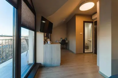a living room with a large window and a balcony at Hotel Avalon Kyustendil in Kyustendil