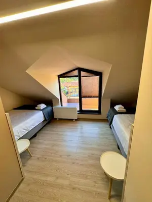a attic room with two beds and a window at Hotel Avalon Kyustendil in Kyustendil