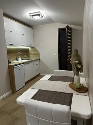 a kitchen with a table and white chairs in a room at Guest House Doni in Sandanski