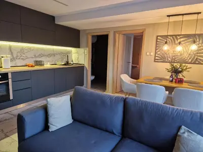a living room with a blue couch and a kitchen at Daisy Garden by the Church in Razlog