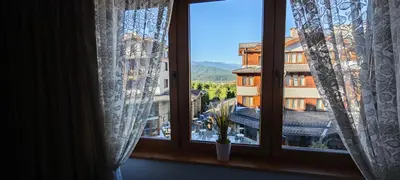 a window with a view of a building at Bansko Pirin Golf & Country Club Blue Mountains View in Razlog