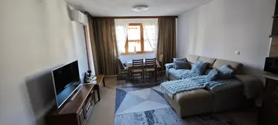 a living room with a couch and a television at Bansko Pirin Golf & Country Club Blue Mountains View in Razlog