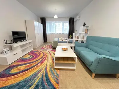 a living room with a blue couch and a colorful rug at Santorini modern and cosy Apt near UNSS and NSA w WiFi in Sofia