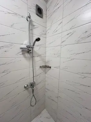 a bathroom with a shower with white marble walls at Santorini modern and cosy Apt near UNSS and NSA w WiFi in Sofia