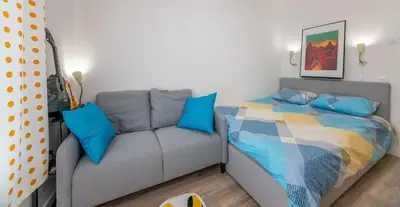 a bedroom with a bed and a couch with blue pillows at Ukulele Place in Sofia
