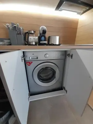 a washing machine in a kitchen under a counter at Lux Apartament 4403 near the ski lift in Bansko