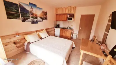 a small bedroom with a bed and a kitchen at Приветливо смарт студио, с изглед към Снежанка и ски писта Пампорово-Стойките in Stoykite