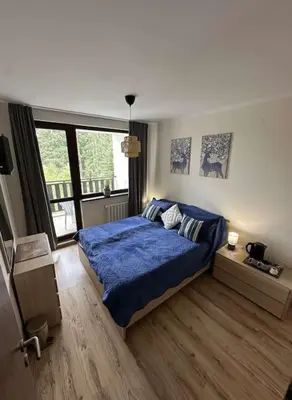 a bedroom with a blue bed and a large window at large apartment in Borovets in Borovets