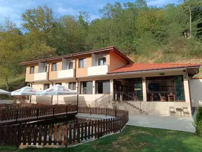 a building with tables and umbrellas in front of it at Комплекс Кантона in Razhishte