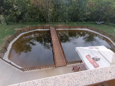 a large pond with a wooden fence around it at Комплекс Кантона in Razhishte