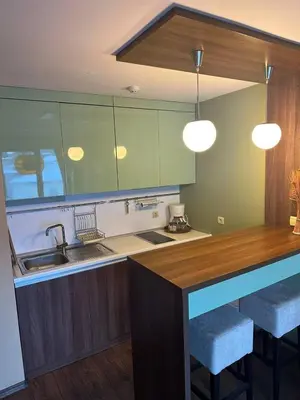 a kitchen with green cabinets and a counter with stools at Luxury Apartment Bansko in Bansko
