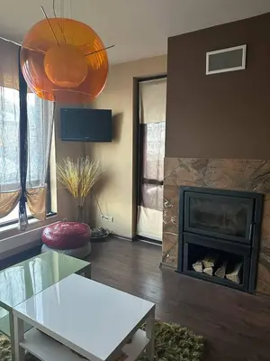 a living room with a fireplace and a white table at Luxury Apartment Bansko in Bansko