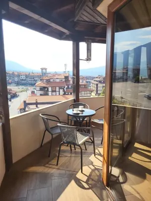 a balcony with a table and chairs and a view at Панорамен Пентхаус - Кабинков лифт - 3 спални in Bansko