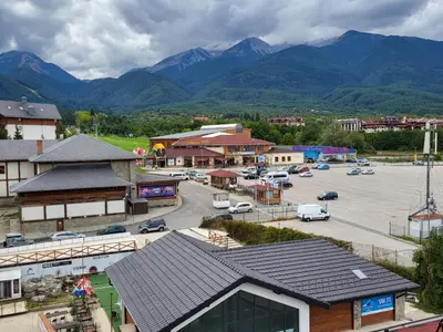 a town with a parking lot with mountains in the background at Панорамен Пентхаус - Кабинков лифт - 3 спални in Bansko