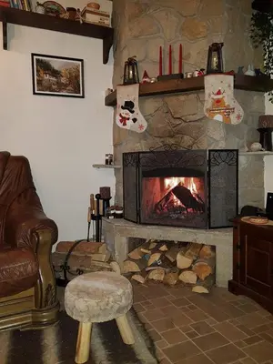 a living room with a stone fireplace and a chair at Nachovata Guest House Stoykite, near Pamporovo in Vodata