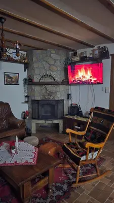 a living room with a stone fireplace with a chair at Nachovata Guest House Stoykite, near Pamporovo in Vodata