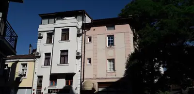 a tall white building sitting next to a tree at Kapana Plovdiv in Plovdiv