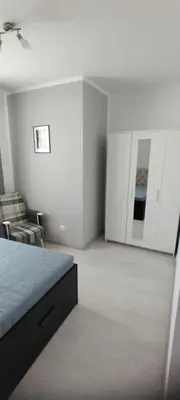 a white bedroom with a bed and a chair at O pulse Sofia apartment in Sofia