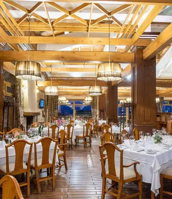 a dining room with tables and chairs and chandeliers at Villa Pirin Golf in Bansko
