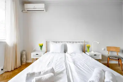 a bedroom with a large white bed with two chairs at Creative 70s-Inspired Stay Center Parking in Sofia