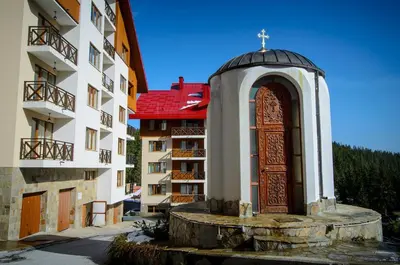 a church with a wooden door in front of a building at Апартамент в Лъки Пампорово комплекс in Pamporovo