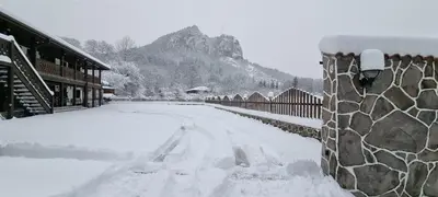 a snow covered street next to a building with a fence at Къща за гости Имало едно време in Smolyan