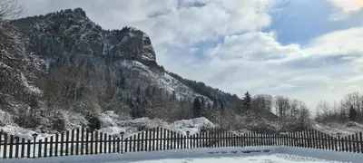 a fence covered in snow in front of a mountain at Къща за гости Имало едно време in Smolyan