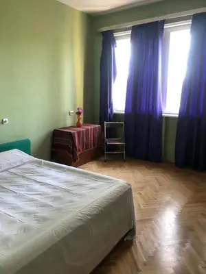 a bedroom with a bed and blue curtains and a table at City Flat Riverside Maritza in Plovdiv