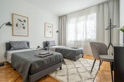 a bedroom with two beds and a chair and a television at Modern and Calm 2BDRM Apt in City Centre in Sofia