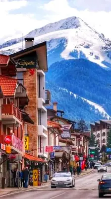 a street in a town with a snow covered mountain at Friendly apartment -top location in Bansko