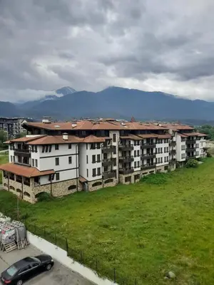 a large apartment building with a car parked in a field at Belvedere Holiday Club H80 in Bansko