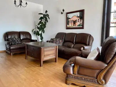 a living room with leather couches and a table at Large Cosy House by a Forest - Treehouse, BBQ, Fireplace & Mountain in Sopot
