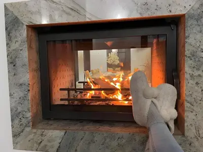 a person with their feet up in front of a fireplace at Large Cosy House by a Forest - Treehouse, BBQ, Fireplace & Mountain in Sopot