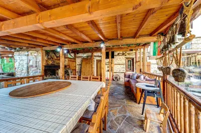 a room with a large wooden table on a balcony at Valkanovi House in Pamporovo