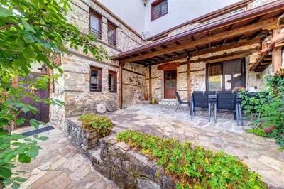 an outdoor patio with chairs and a stone building at Valkanovi House in Pamporovo