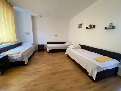 a room with three beds and a wooden floor at BASSO Guest Rooms in Perushtitsa
