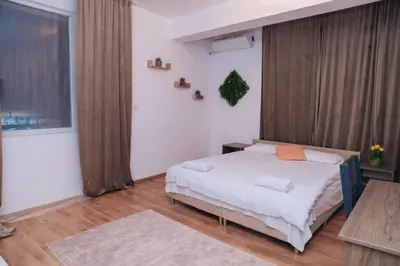 a bedroom with a bed with white sheets and orange pillows at BASSO Guest Rooms in Perushtitsa