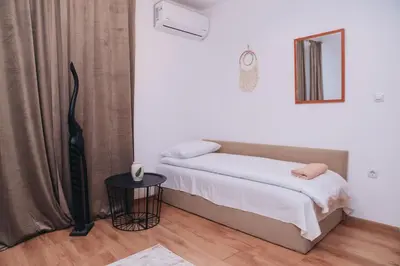 a small bedroom with a bed and a table at BASSO Guest Rooms in Perushtitsa