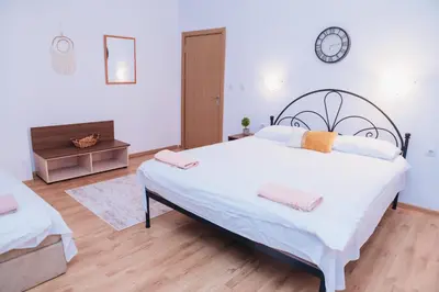 a bedroom with a large bed and a clock on the wall at BASSO Guest Rooms in Perushtitsa