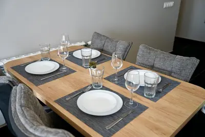 a wooden table with plates and wine glasses on it at AveNew Luxury Apartment 3 in Sofia