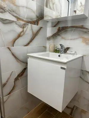 a bathroom with a white sink and a marble wall at Bibi Central Apartment Plovdiv in Plovdiv