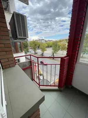 a balcony with a red railing and a view of a street at Apartment Iztochen blvd, free parking in Plovdiv