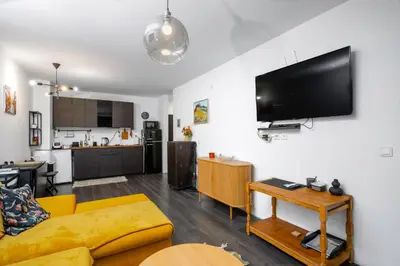 a living room with a couch and a tv on a wall at Cozy 1BD Flat Close to the City Center by Flat Mаnager in Sofia