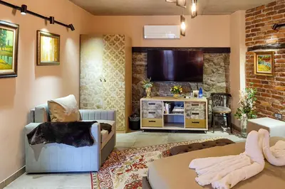 a living room with a couch and a tv at Къща за гости Casa La Tinozza in Hisarya